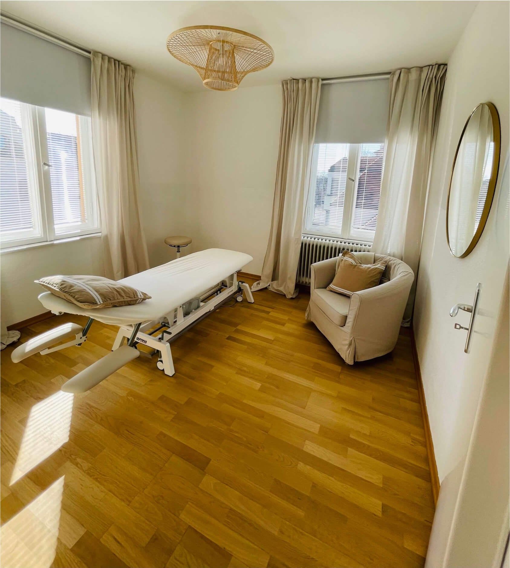 Ruhiger Praxisraum mit Sessel, Therapieliege und Spiegel