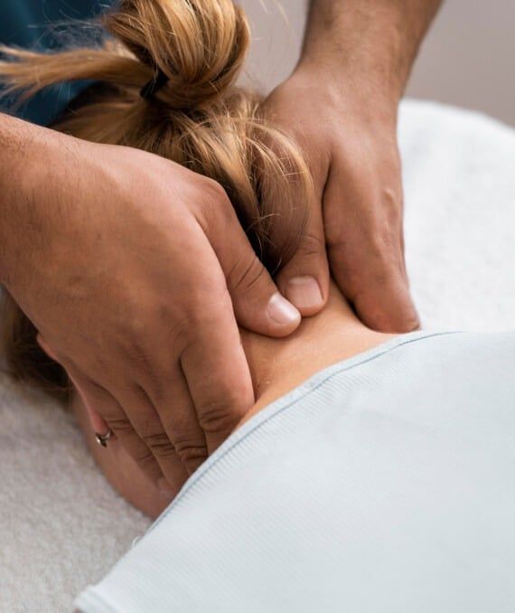 Massage im Nackenbereich Ein Physiotherapeut massiert den Nacken einer Klientin mit seinen Händen.
