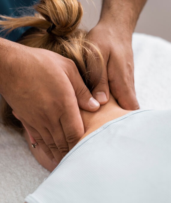Ein Physiotherapeut massiert den Nacken einer Klientin mit seinen Händen.